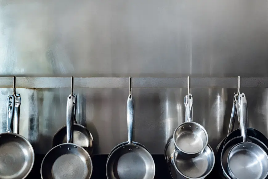 pots and pans hanging on a stainless steel wall